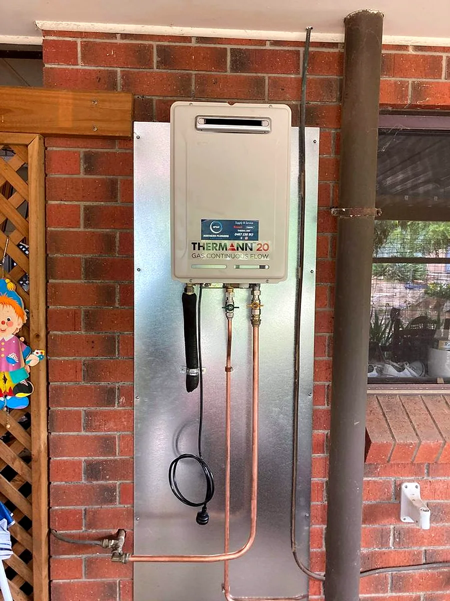 Gas continuous flow hot water system installed on a brick wall